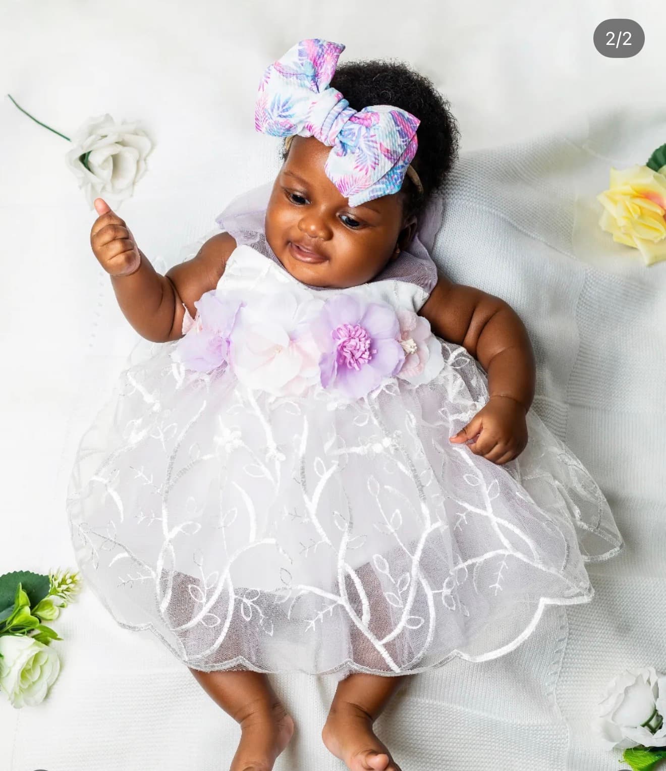 Baby in a floral headband reaching for a rose