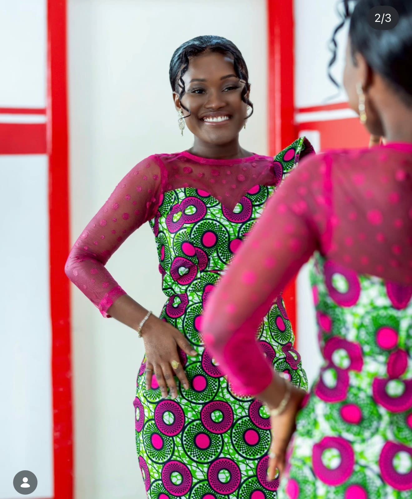 Woman in a colorful print dress smiling into a mirror